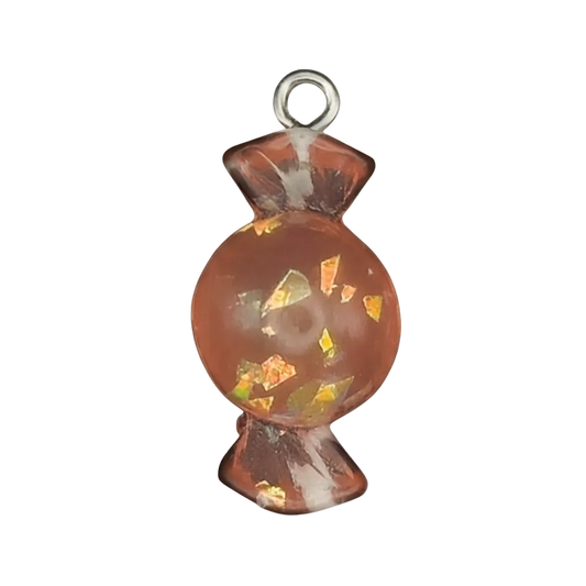 close-up orange wrapped candy resin charm with gold flakes on black background