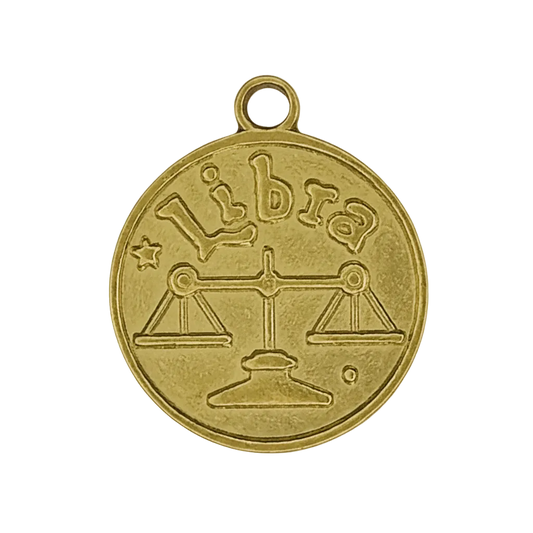 Close-up of round gold-tone charm with Libra scales and the word 'Libra'.