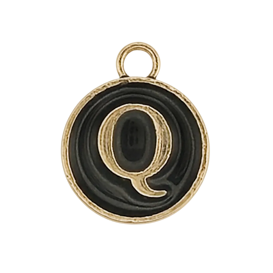 close-up of round black and gold charm with letter Q