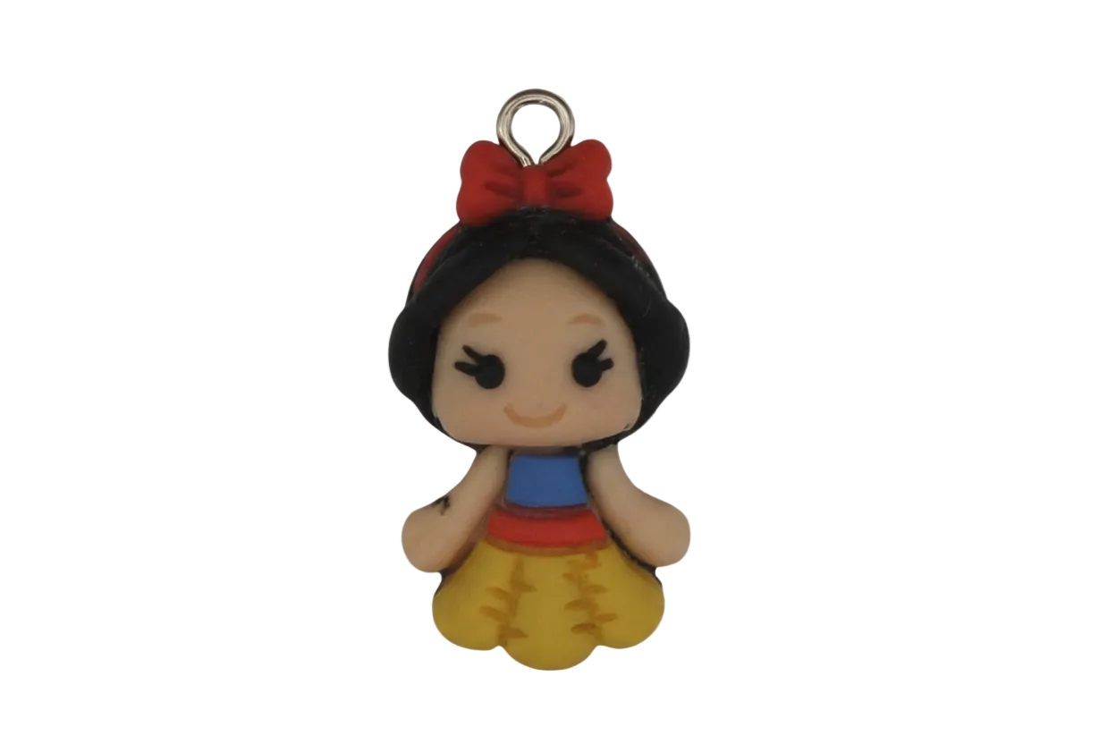 close-up of small cartoon princess charm with red bow and yellow skirt on a black background