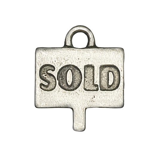 close-up of small silver charm shaped like a sign with the word SOLD