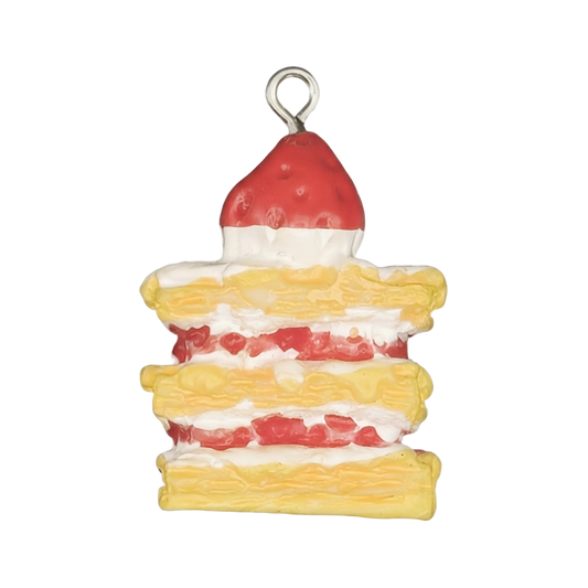close-up of a layered strawberry cake enamel charm on a black background