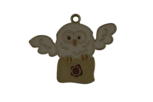 close-up of enamel owl holding a sealed envelope charm on black background