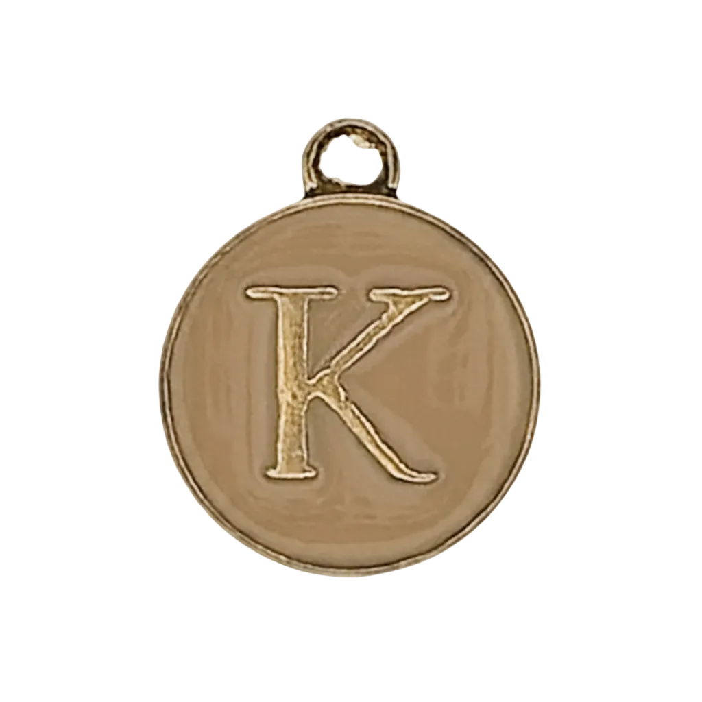 close-up of round gold-tone charm with engraved letter K