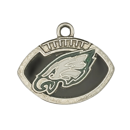 close-up of football-shaped metal charm with eagle head emblem in black and green enamel