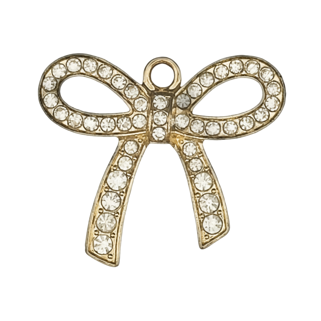 Close-up of a gold-tone bow charm with clear rhinestones on a black background.