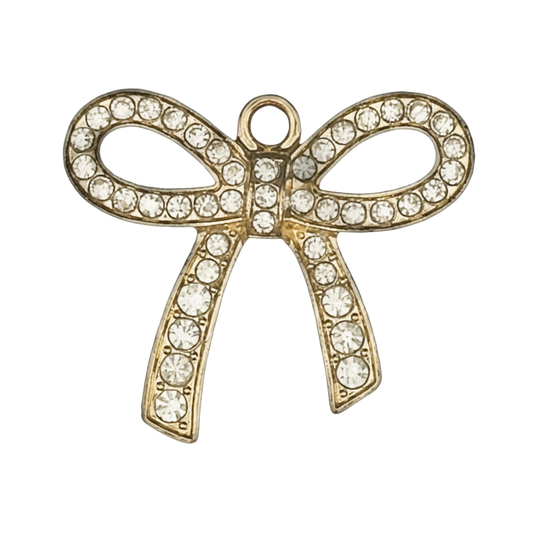 Close-up of a gold-tone bow charm with clear rhinestones on a black background.