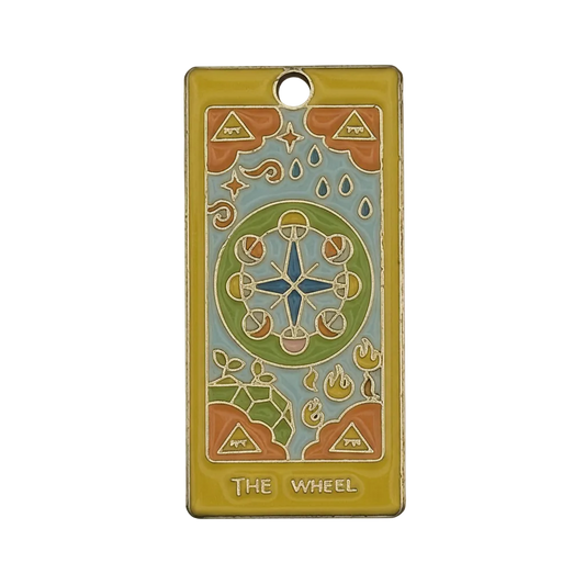 Close-up of rectangular enamel charm with 'THE WHEEL' tarot design in a gold-tone frame.