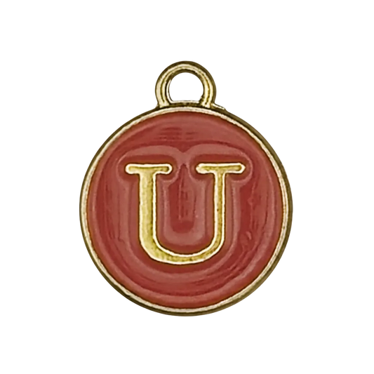 Close-up of a round red enamel charm with a gold letter U on a black background.
