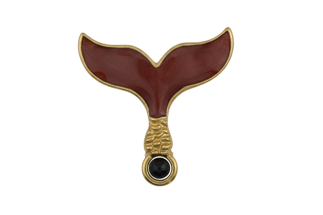 close-up of burgundy enamel whale tail charm with gold-tone edges on black background