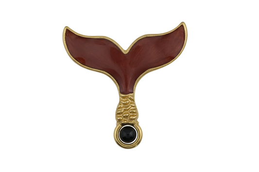close-up of burgundy enamel whale tail charm with gold-tone edges on black background