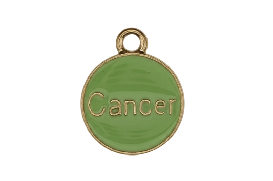 close-up of round green enamel charm reading 'Cancer' with gold edging on black background