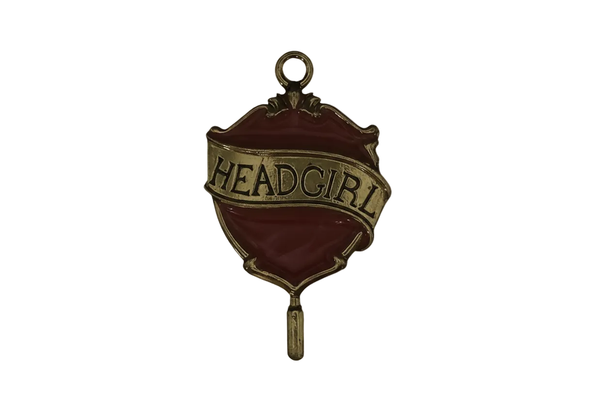 close-up of red and gold 'HEAD GIRL' badge charm on black background