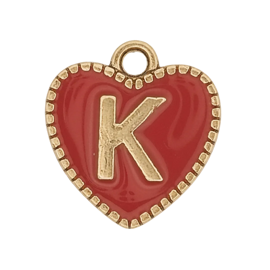 Close-up red enamel heart charm with gold letter K and beaded gold border on black background.