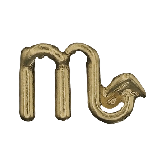 Close-up of gold Scorpio zodiac symbol charm on black background.