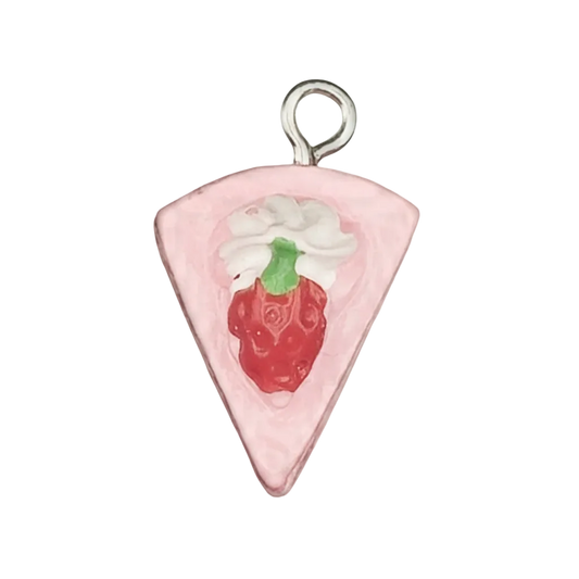 close-up of a pink cake slice charm with a red strawberry and white cream on a black background