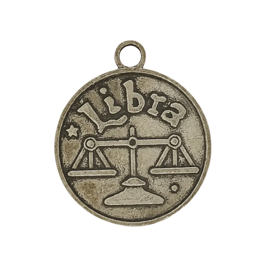 close-up of round bronze libra zodiac charm with scales and the word libra