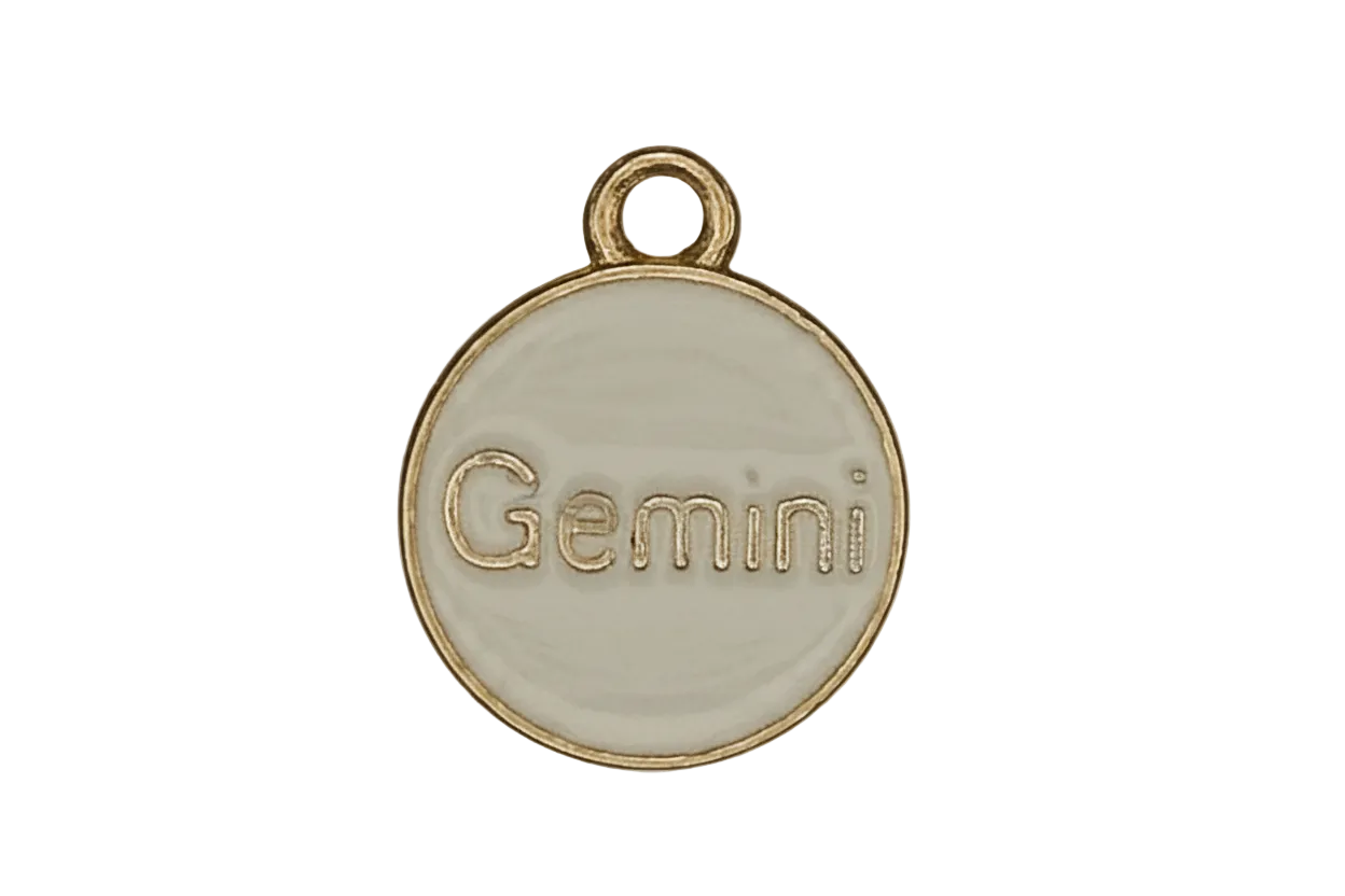 close-up of round cream enamel charm with gold 'Gemini' text