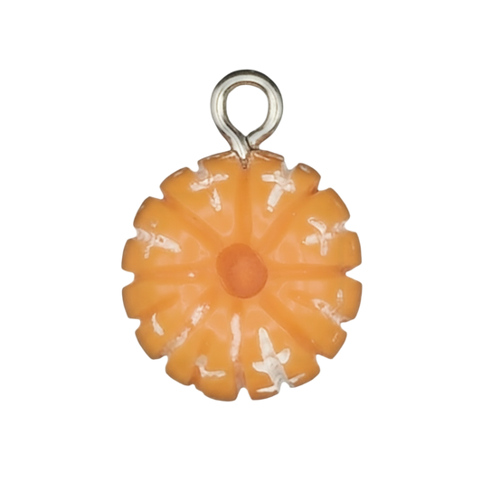 close-up of small orange enamel flower charm on black background