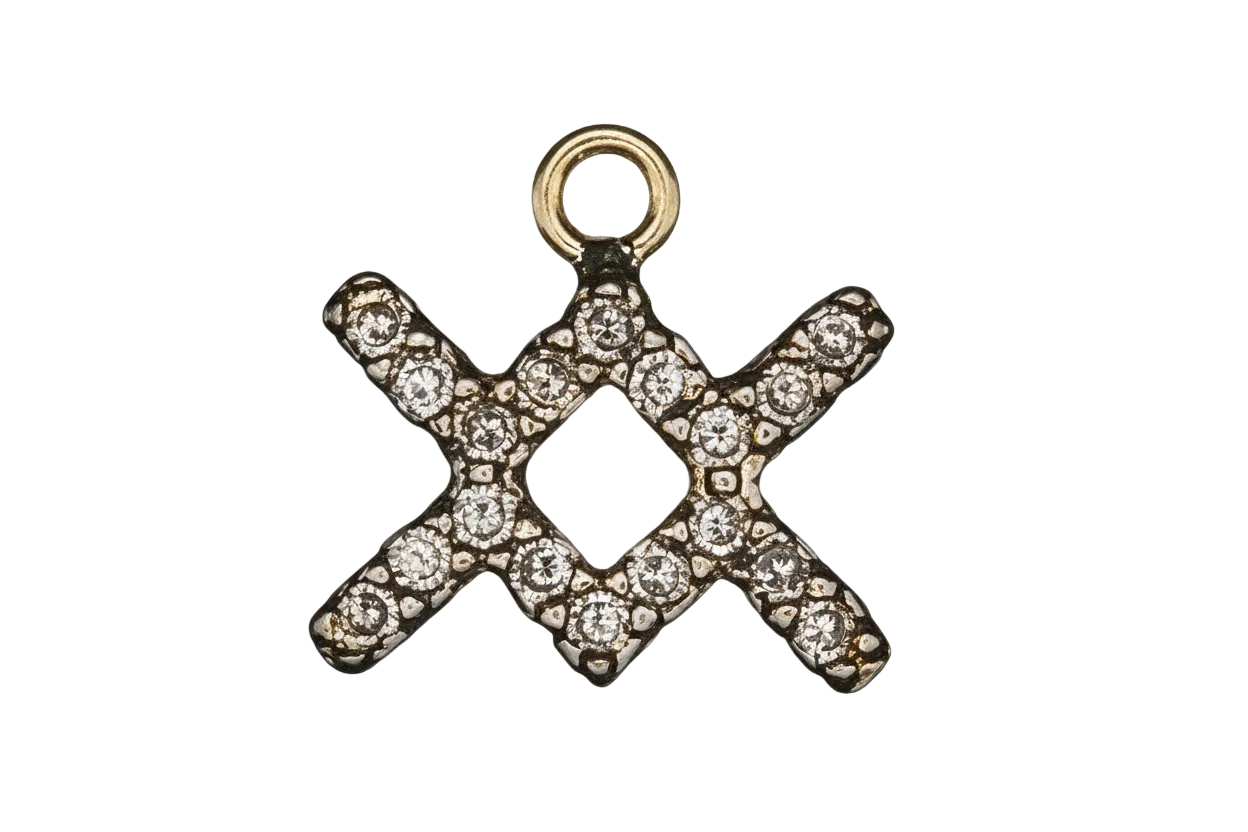 close-up of a small gold-tone XO charm with clear stones on a black background