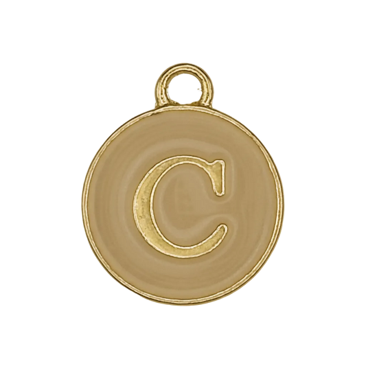Close-up of round gold-tone charm with letter C on beige background