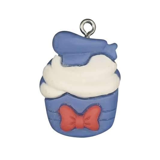 close-up of blue cupcake charm with white frosting and red bow on black background