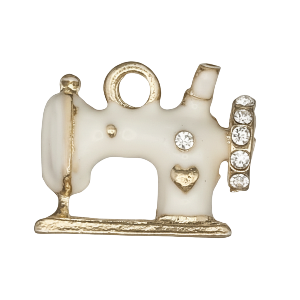 close-up of white enamel sewing machine charm with gold trim and clear stones
