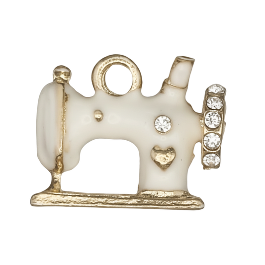 close-up of white enamel sewing machine charm with gold trim and clear stones