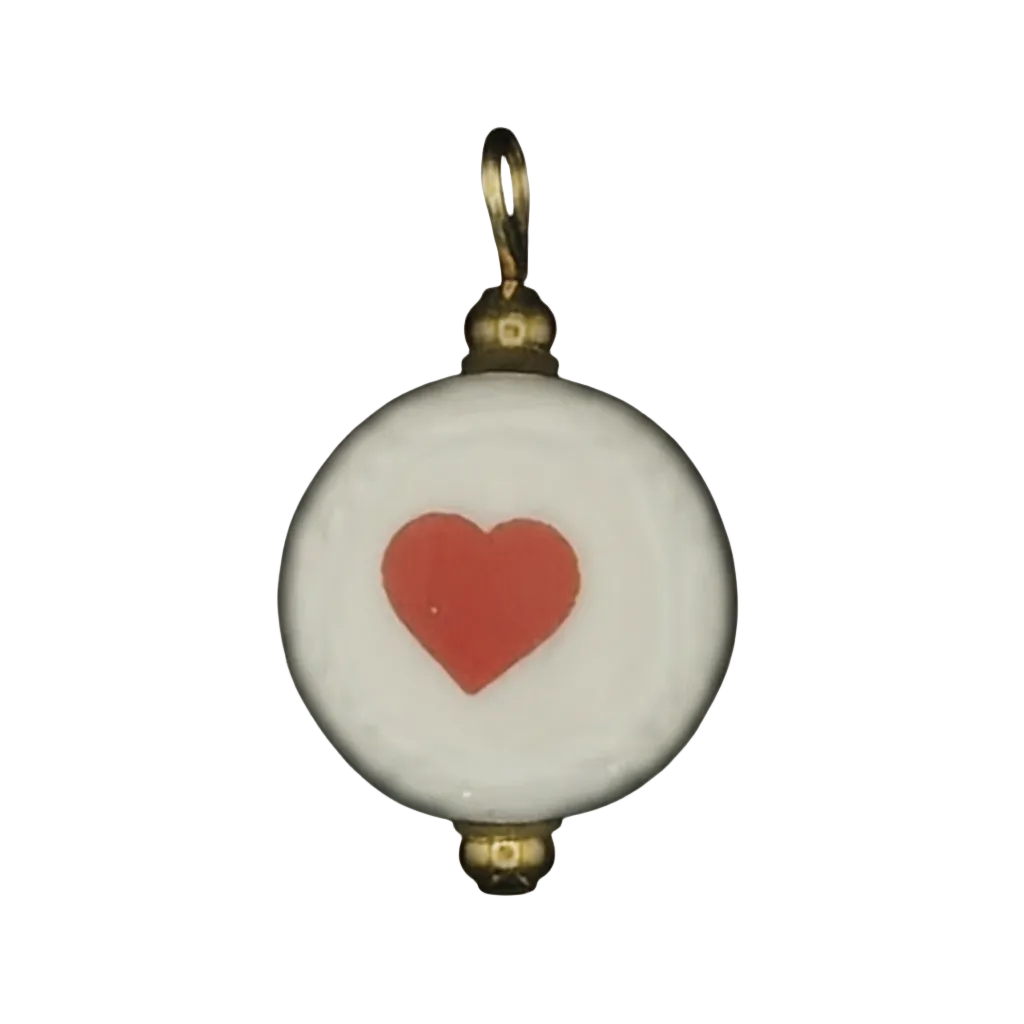 close-up of round white charm with red heart and gold-tone accents