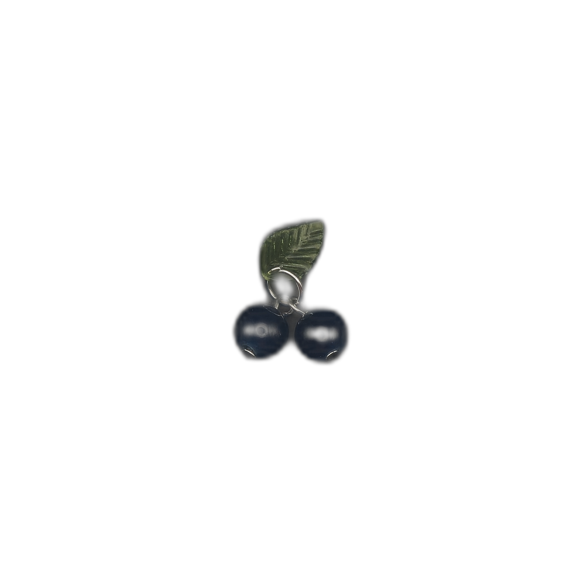 full view of small charm with two dark blue berries and a green leaf centered on black background