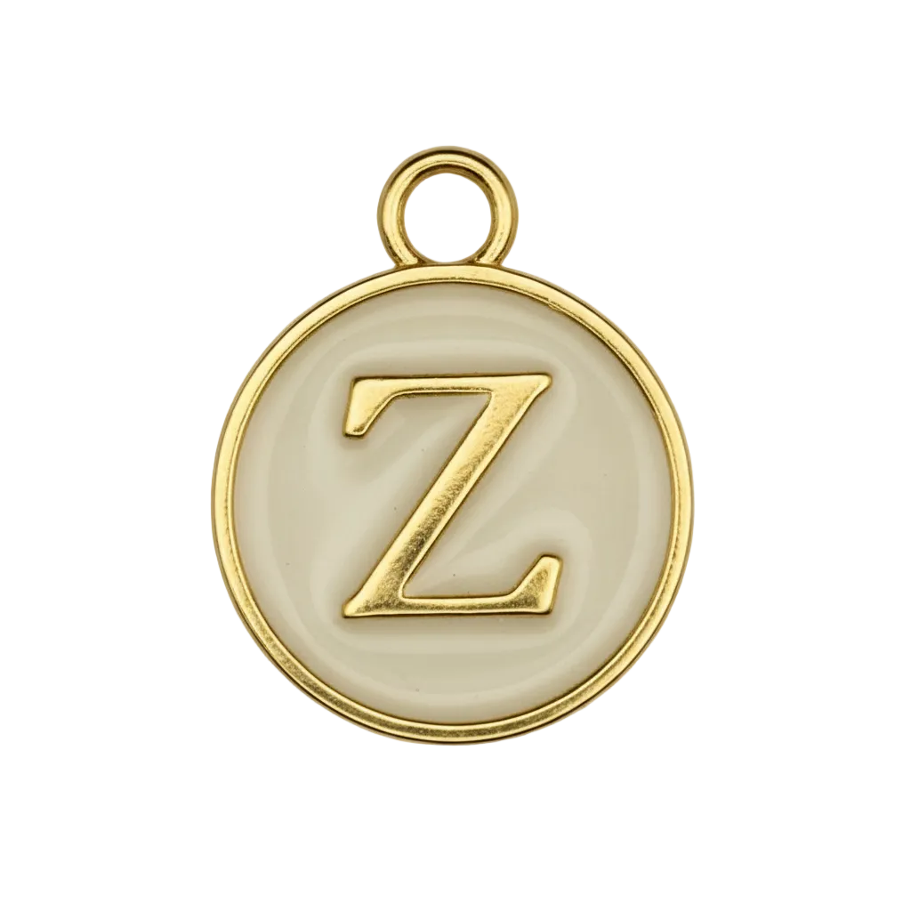 close-up of round gold-tone charm with raised letter Z on cream background