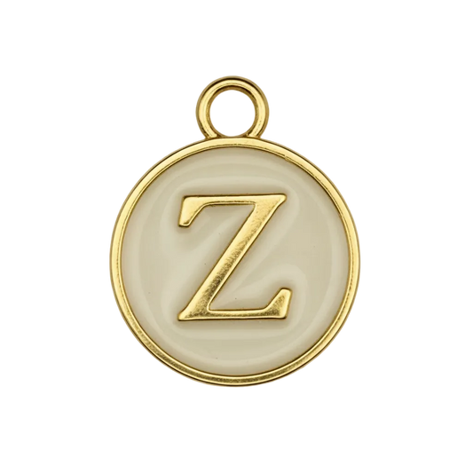 close-up of round gold-tone charm with raised letter Z on cream background