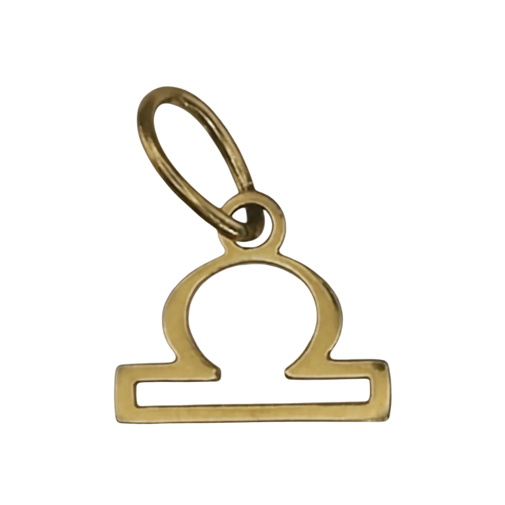 close-up of gold-tone Libra zodiac charm on black background