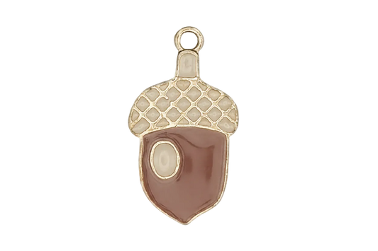 close-up of a small acorn-shaped enamel charm with brown body, cream cap, and gold outline on black background