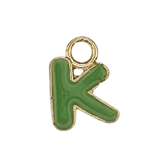 close-up of small green letter K charm with gold outline on black background