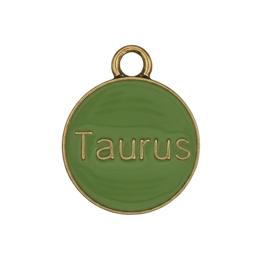 close-up of round green Taurus charm with gold-tone edge on black background