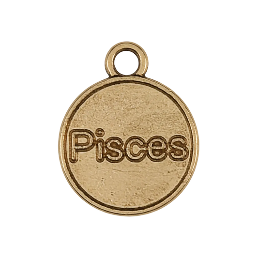 Close-up of a small round gold-tone charm engraved with the word Pisces on a black background.