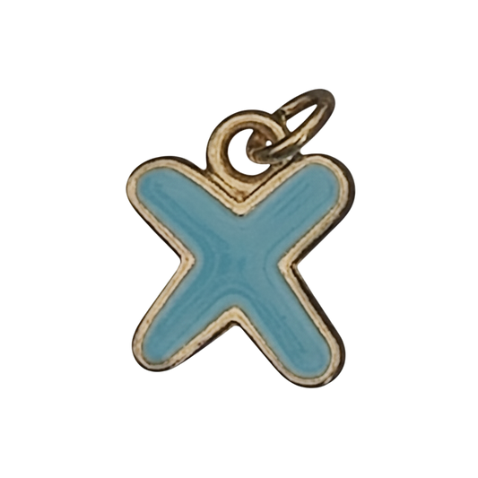 close-up of a small blue letter X charm with gold-tone trim on a black background